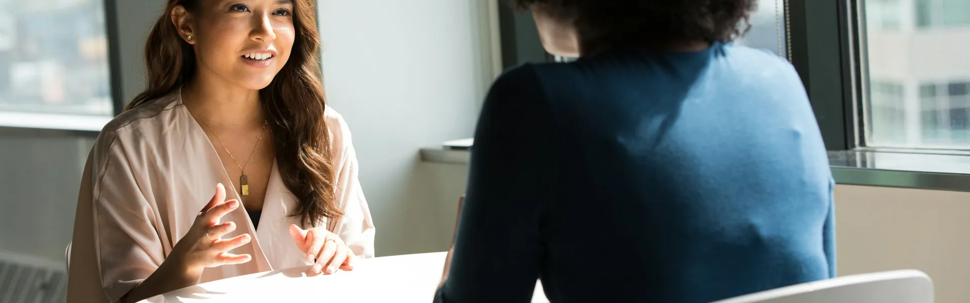 Dos mujeres conversan sentadas frente a frente