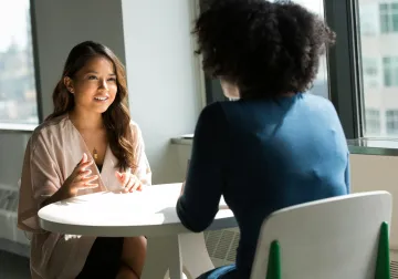 Dos mujeres conversan sentadas frente a frente