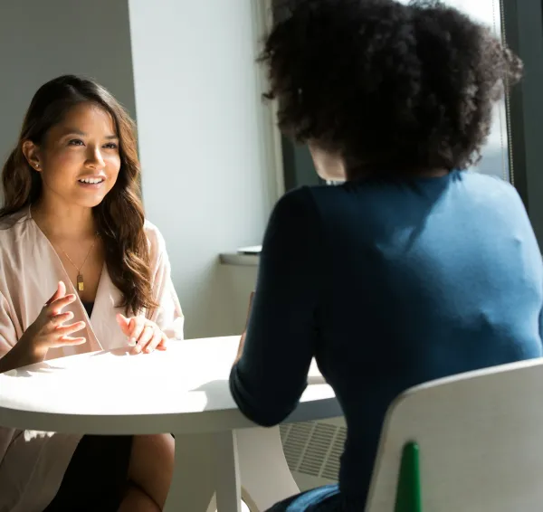 Dos mujeres conversan sentadas frente a frente
