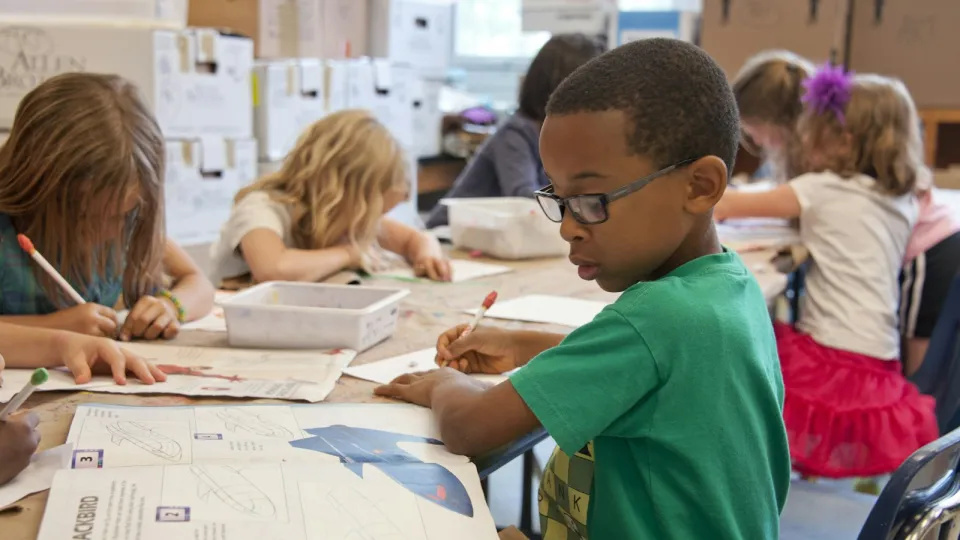 Niños dibujando y aprendiendo en una mesa compartida